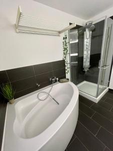 een badkamer met een wit bad en een douche bij Appartement W@llstreet in Nordhausen