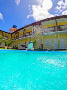 a swimming pool in front of a building with water at Pousada Corais de Maracajaú in Maracajaú