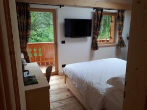 a bedroom with a bed and a flat screen tv at Rifugio Lago D'Ajal in Col
