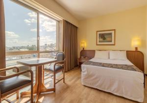 a hotel room with a bed and a desk and a window at Ritter Hotéis in Porto Alegre