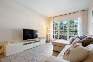 a living room with a couch and a tv at Hauzify I Apartament Bòvila Mar in S'Agaro