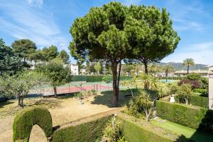 a park with a tree and a tennis court at Hauzify I Apartament Bòvila Mar in S'Agaro