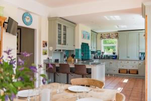 een keuken met witte kasten en een tafel met stoelen bij Burleigh House by Bloom Stays in Charing