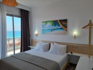 a bedroom with a bed with a view of the beach at Anxhelos Hotel in Himare