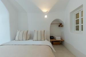 a white bedroom with a bed and a window at Crown of Fira in Firostefani +42 photos