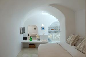a white room with a bed and a table at Crown of Fira in Firostefani