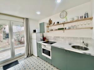 uma cozinha com armários verdes, um lavatório e uma janela em La Villa des Oiseaux - Coeur de Vichy em Vichy