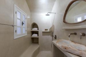 ein Badezimmer mit einem Waschbecken, einer Badewanne und einem Spiegel in der Unterkunft Crown of Fira in Firostefani