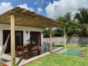 a wooden pergola with a table and a pool at Os Navegantes - Casa Mar in Amontada