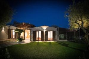 a house with a green yard at night at La Manica Rooms in Milazzo