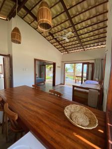 a dining room with a wooden table and a bed at Os Navegantes - Casa Mar in Amontada