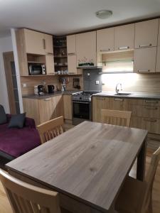 a kitchen with a wooden table with chairs and a couch at Apartmán Family s výhľadom na Choč in Lúčky