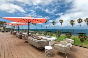 una terraza con sillas, mesas y sombrilla en La Jolla Cove Suites en San Diego