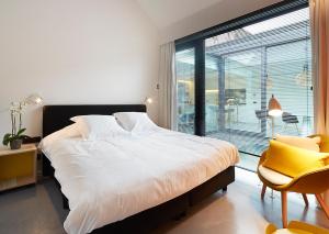 ein Schlafzimmer mit einem Bett, einem Fenster und einem Stuhl in der Unterkunft B&B Ceder10 in Kruibeke