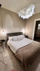 una camera da letto con un grande letto bianco e un lampadario a braccio di Casa Adriana a Siracusa