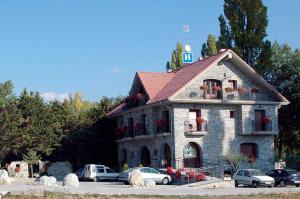 un bâtiment en pierre avec des voitures garées dans un parking dans l'établissement Hotel Restaurante Santa Elena, à Sabiñánigo