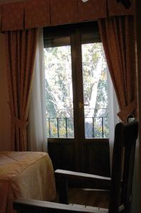 Habitación con ventana, cama y puerta en Hotel Restaurante Santa Elena, en Sabiñánigo