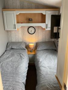 dwa łóżka w małym pokoju z zegarem na ścianie w obiekcie Golden Palm Resort TM5 w mieście Chapel St Leonards