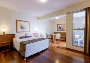 ein Hotelzimmer mit Bett, Tisch und Stühlen in der Unterkunft Ritter Hotéis - Em frente à Rodoviária de Porto Alegre in Porto Alegre + 90 Fotos