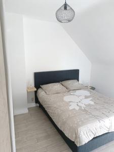 a bed in a bedroom with a white wall at Charmante maison en pierres in Langon