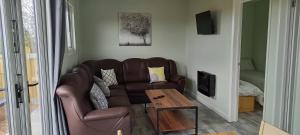 a living room with a brown couch and a table at Grenada Garden Lodges in Ingoldmells