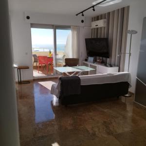 カディスにあるAtico Apartamento Loft Playa Victoria Cadizのリビングルーム(ベッド1台、テレビ、テーブル付)