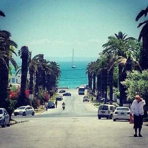 a street with cars and a boat in the ocean at Appartement 2 à Carthage byrsa in Douar ech Chott
