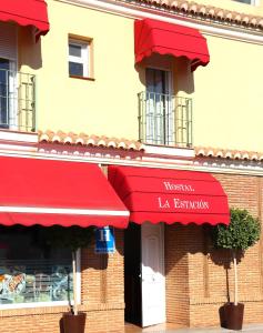 a restaurant with red awnings on a building at HOSTAL LA ESTACION in Benajarafe