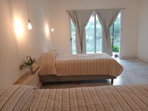 a bedroom with two beds and a window with a door at Casa Tierra Verde Oliva in Ciudad Lujan de Cuyo