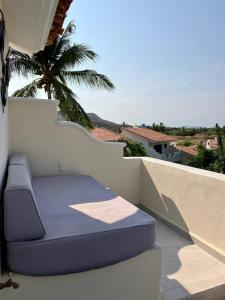 a blue bed on a balcony with a palm tree at Villa Flamingo Golf Ixtapa in Ixtapa