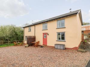 a house with a red door and a gravel yard at Apple Cottage in Crediton