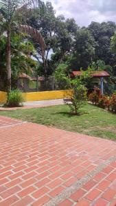 a brick walkway next to a park with trees at Cabaña Campestre in La Pintada