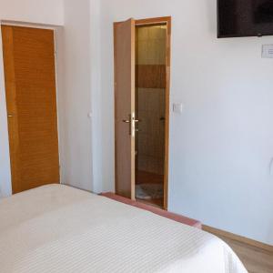 a bedroom with a bed and a door to a shower at Apartmani Radovac in Zaton