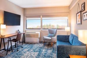 una camera d'albergo con scrivania, divano e tavolo di Four Points by Sheraton Norwood Conference Center a Norwood