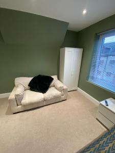 Cette chambre dispose d'un canapé blanc avec un oreiller noir. dans l'établissement Modern En-Suite Rooms Town Centre Self-Check In, à Barnsley