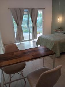 1 dormitorio con mesa, 2 sillas y 1 cama en Casa Tierra Verde Oliva en Luján de Cuyo