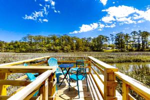 una terraza con 3 sillas y una mesa. en Charming Cottage, en Shallotte