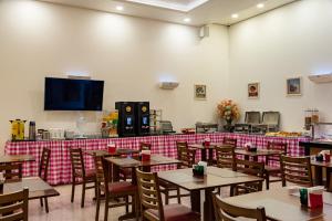 a dining room with tables and chairs and a tv at Hotel Santos Dumont Aeroporto SLZ in São Luís