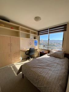 a bedroom with a bed and a desk and a window at Rincones del Placer, un lugar repleto cariño in Valparaíso