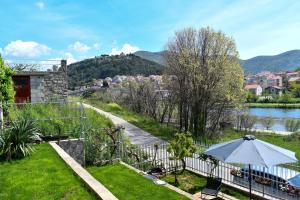 un jardin avec un parasol à côté d'une rivière dans l'établissement Studio Rio, à Trebinje