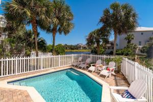 uma piscina com cadeiras e uma cerca e palmeiras em Destin Pointe 3586 - Emerald Breeze Hideaway em Destin