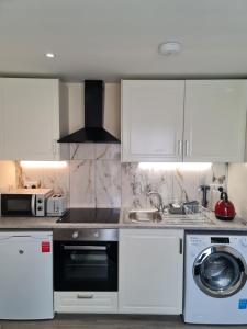 a kitchen with white cabinets and a washer and dryer at Cosy Garden Studio near Dublin Airport in Dublin