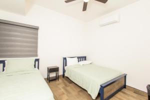 two beds in a room with white walls and wood floors at Residence 4 in Puerto Peñasco