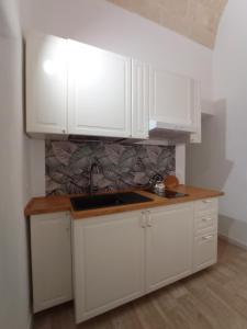 a white kitchen with white cabinets and a sink at LUNA in Monopoli +5 photos