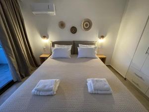 a bedroom with a bed with two white towels on it at Golden Evelyn in Agia Paraskevi