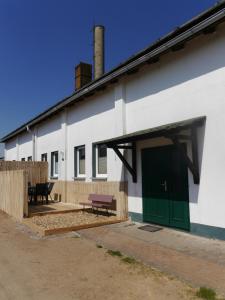a white building with a green door and a bench at Familienurlaub auf dem Land - haustierfreundlich - 10 Minuten von Templin in Milmersdorf