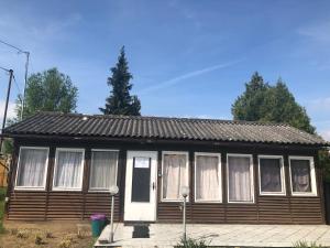 Casa de madera pequeña con puerta blanca y ventanas en Hegykői Viola, en Hegykő