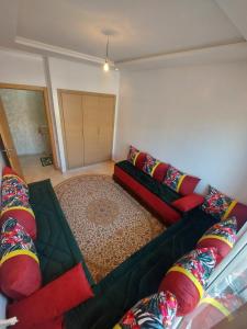 - un salon avec un canapé vert et des oreillers rouges dans l'établissement Lux Apartment In Bouznika With Pool, à Bouznika
