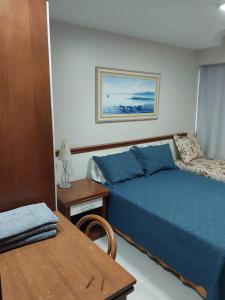 Un dormitorio con una cama azul y una mesa en Pé na areia Praia da Costa, en Vila Velha