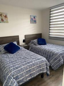 2 łóżka w sypialni z niebieską i białą pościelą w obiekcie Departamento a minutos del centro de Puerto Montt Pelluco alto w mieście Puerto Montt